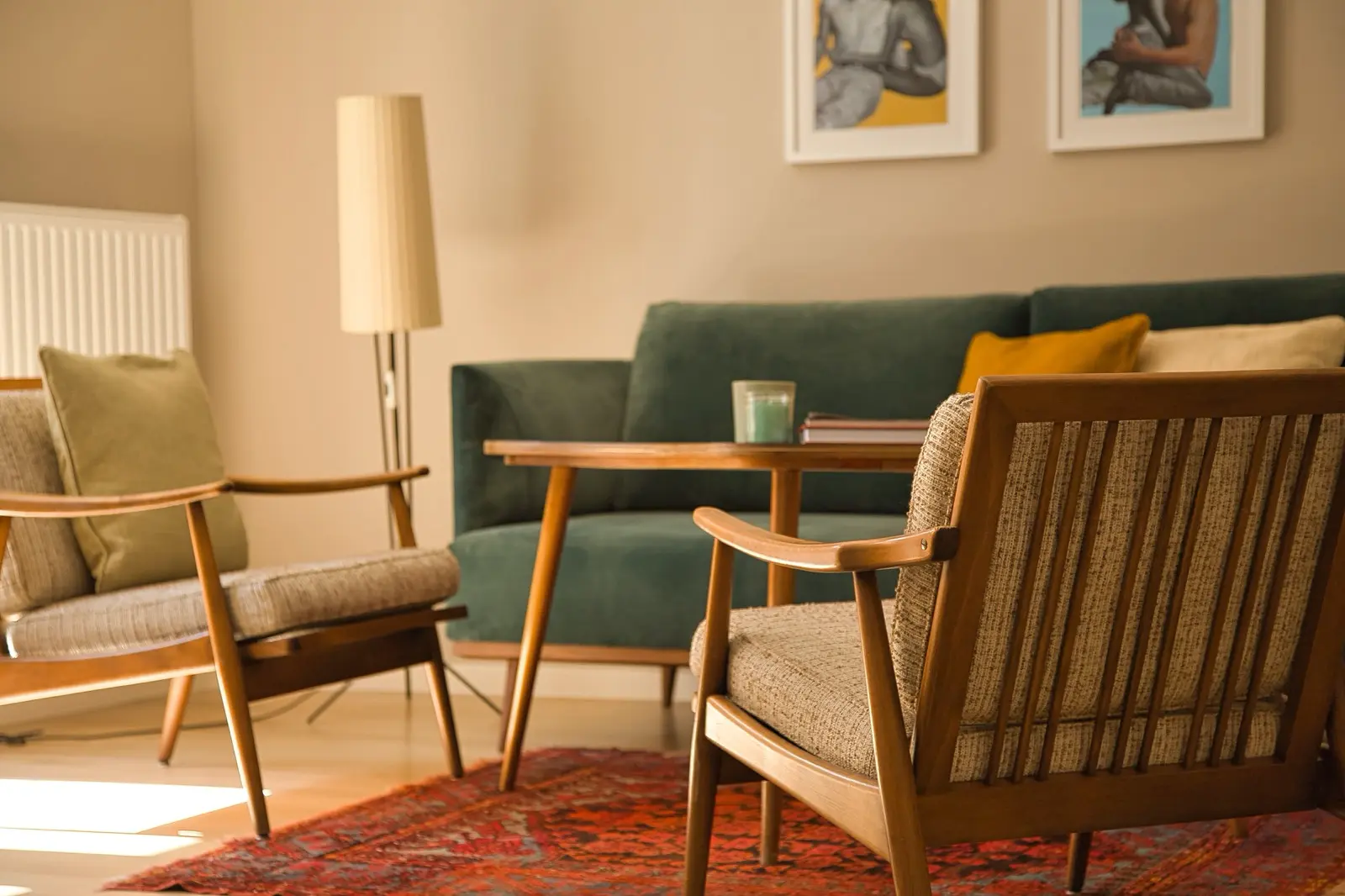 Wohnzimmer mit grüner Samtcouch, Holzmöbeln und rotem Teppich.