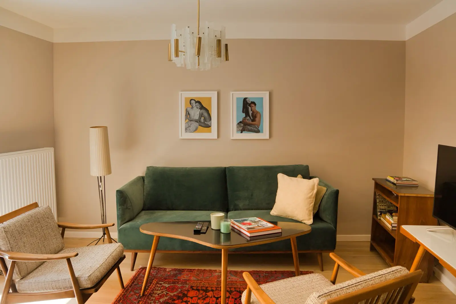 Wohnzimmer mit grüner Couch, warmen Holztönen und klassischem Kronleuchter.