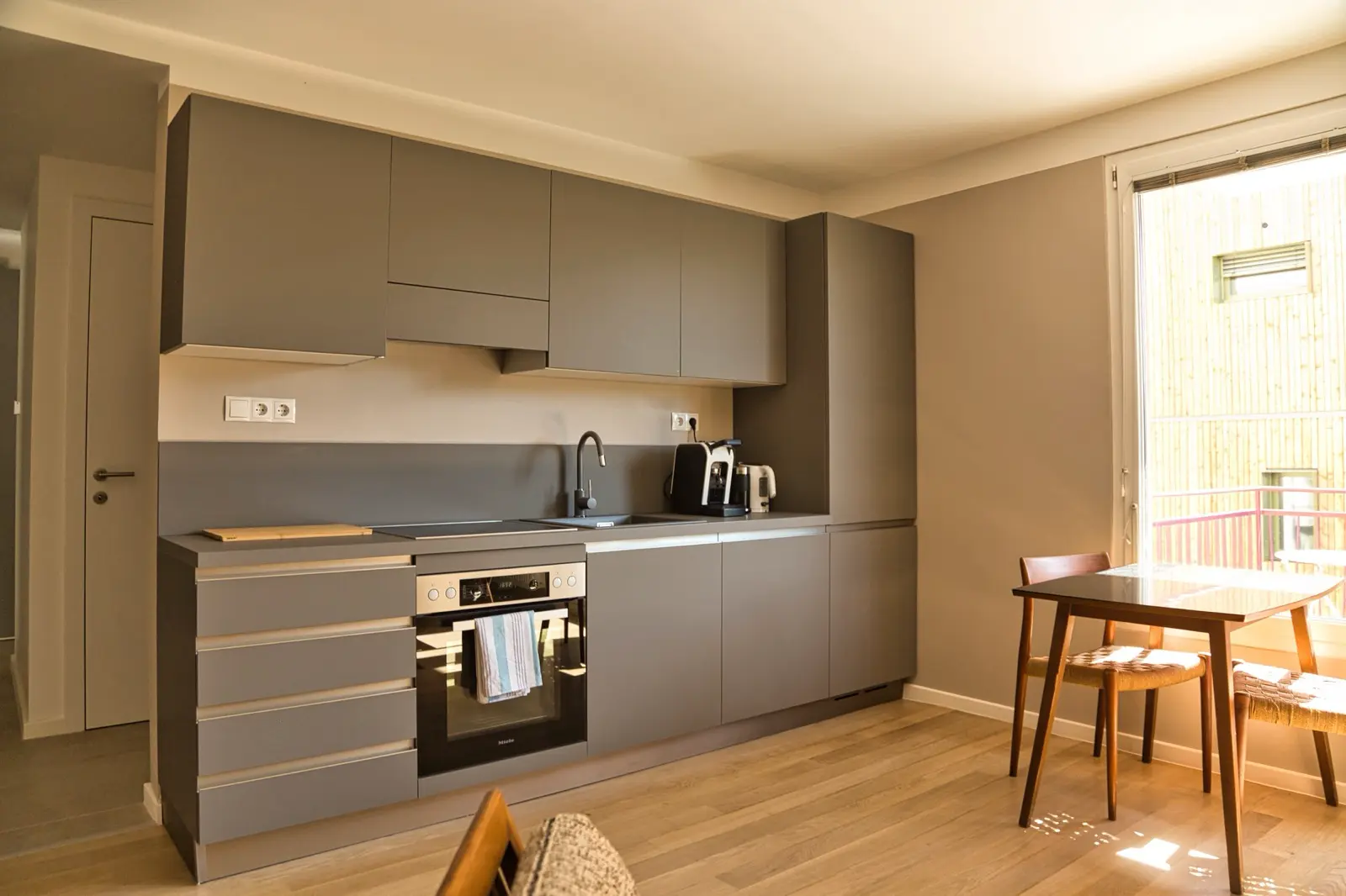 Küchenzeile mit schwarzen Schrankfronten und Edelstahlgeräten.