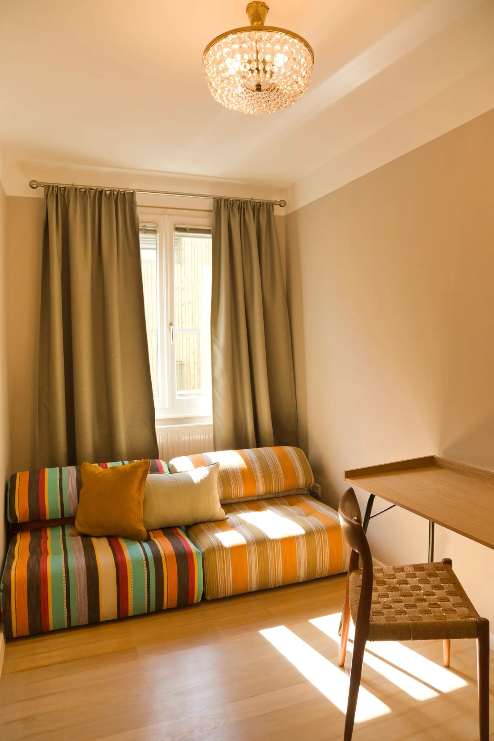 Schlafzimmer mit bodentiefem Fenster, goldenem Vorhang und Sitzecke.