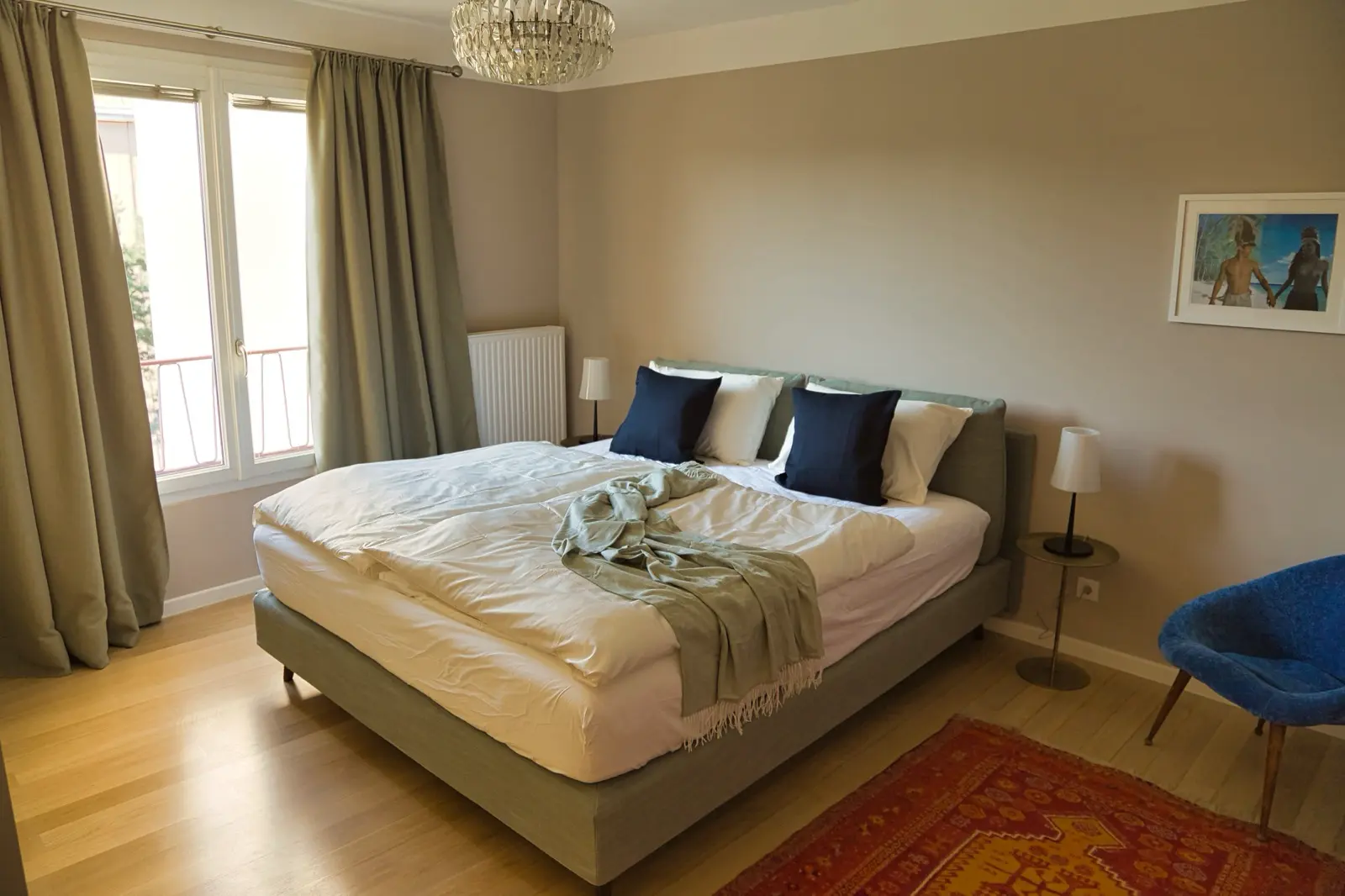 Hauptschlafzimmer mit beigem Bettgestell und blauen Akzenten.