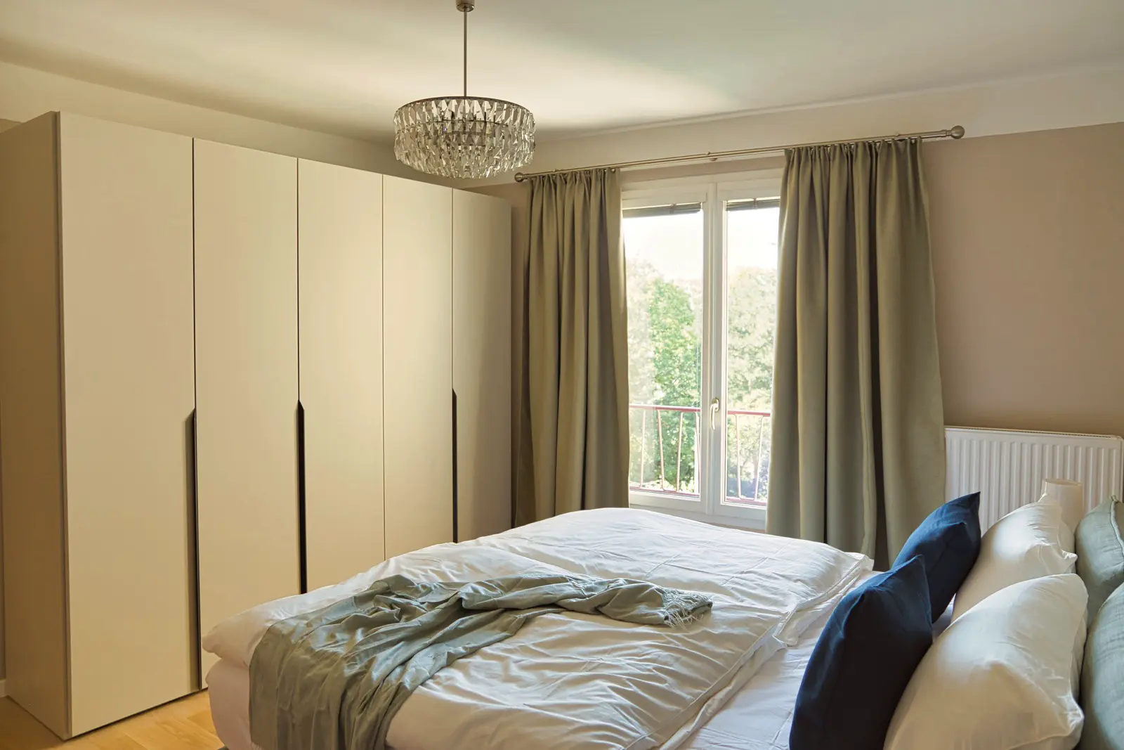 Lichtdurchflutetes Schlafzimmer mit Kleiderschrank und großem Fenster.