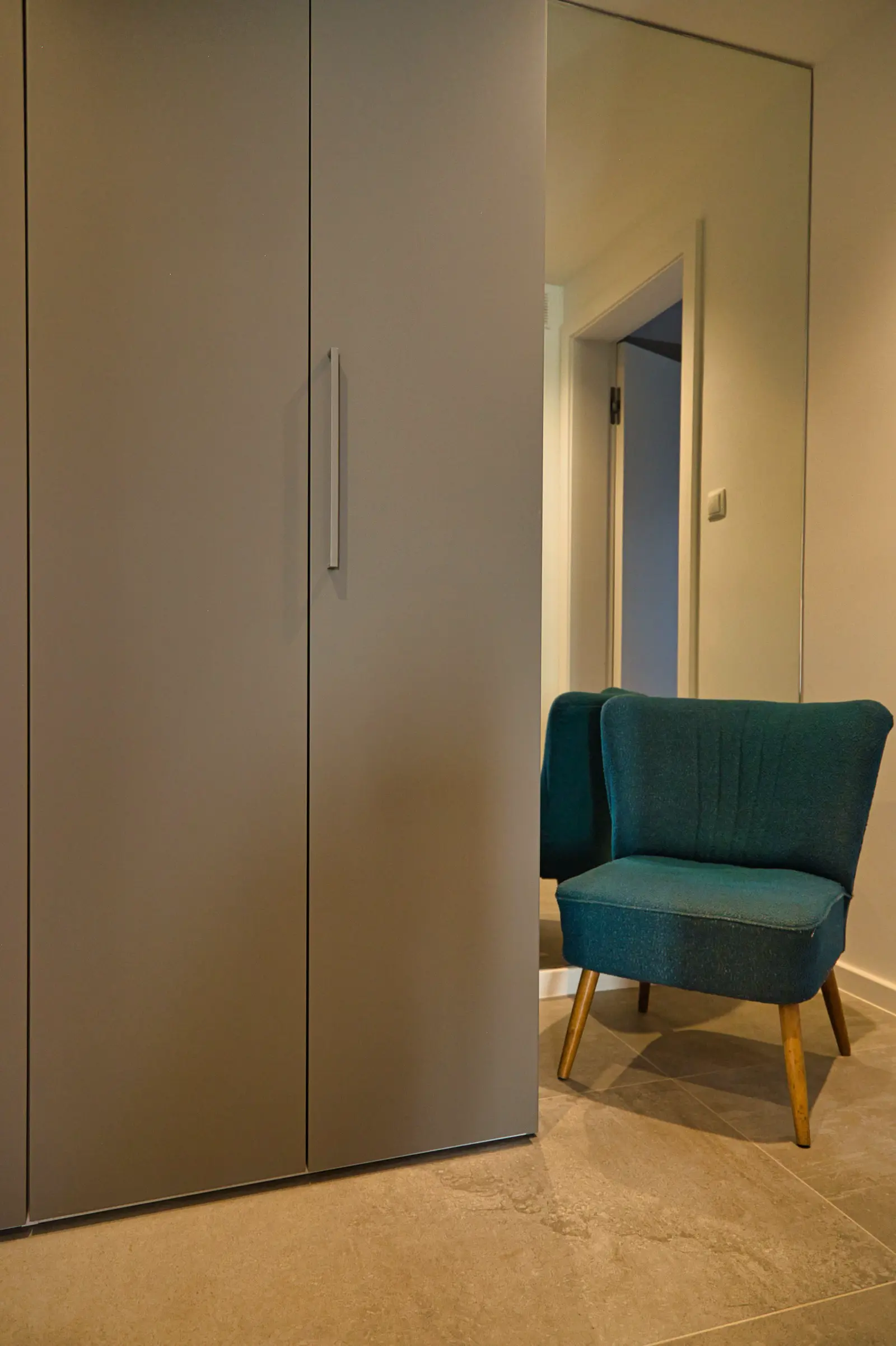 Schrankwand mit türkisfarbenem Akzentstuhl.
