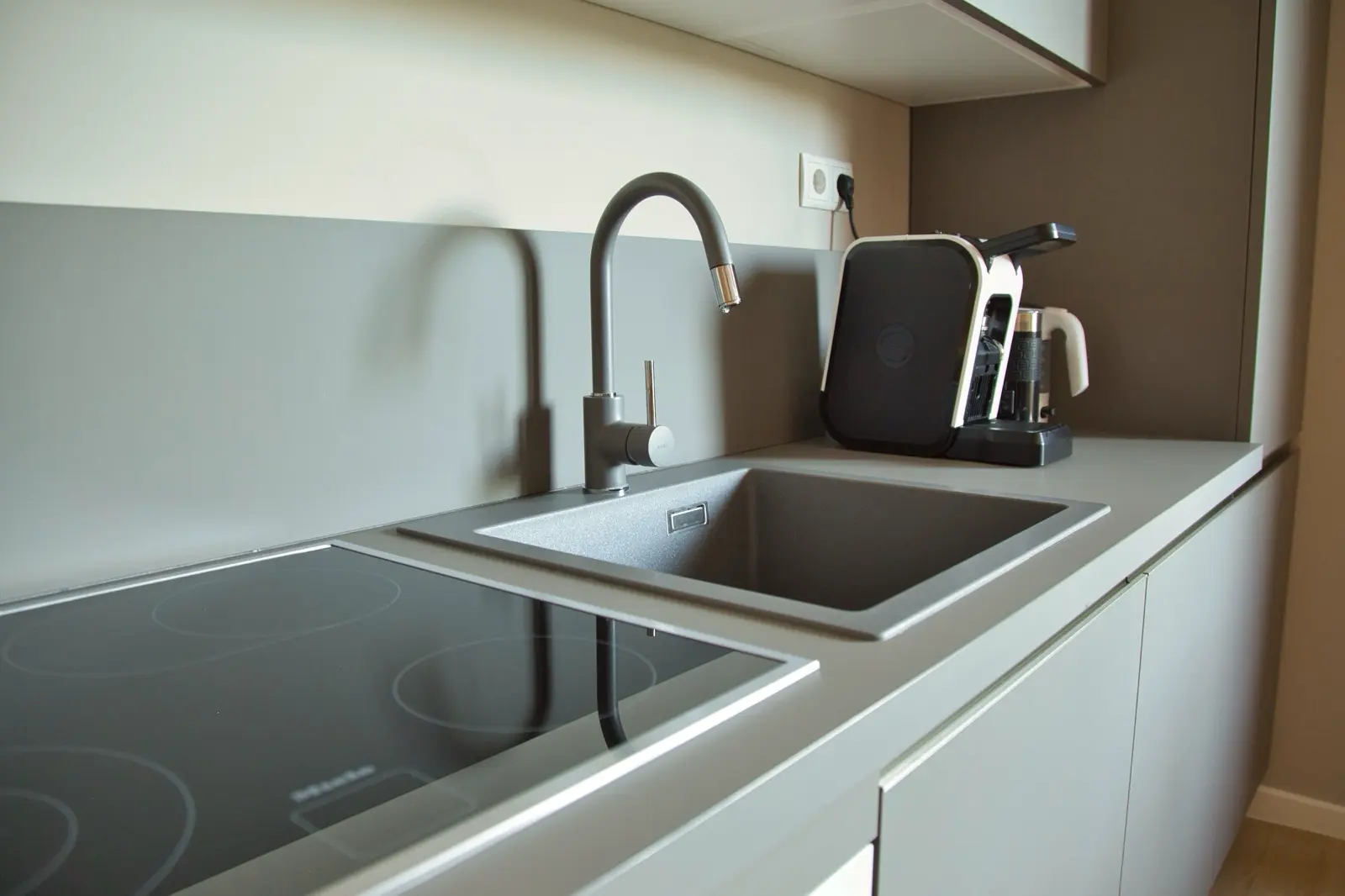 Küchenzeile mit grauer Arbeitsplatte und Induktionskochfeld.