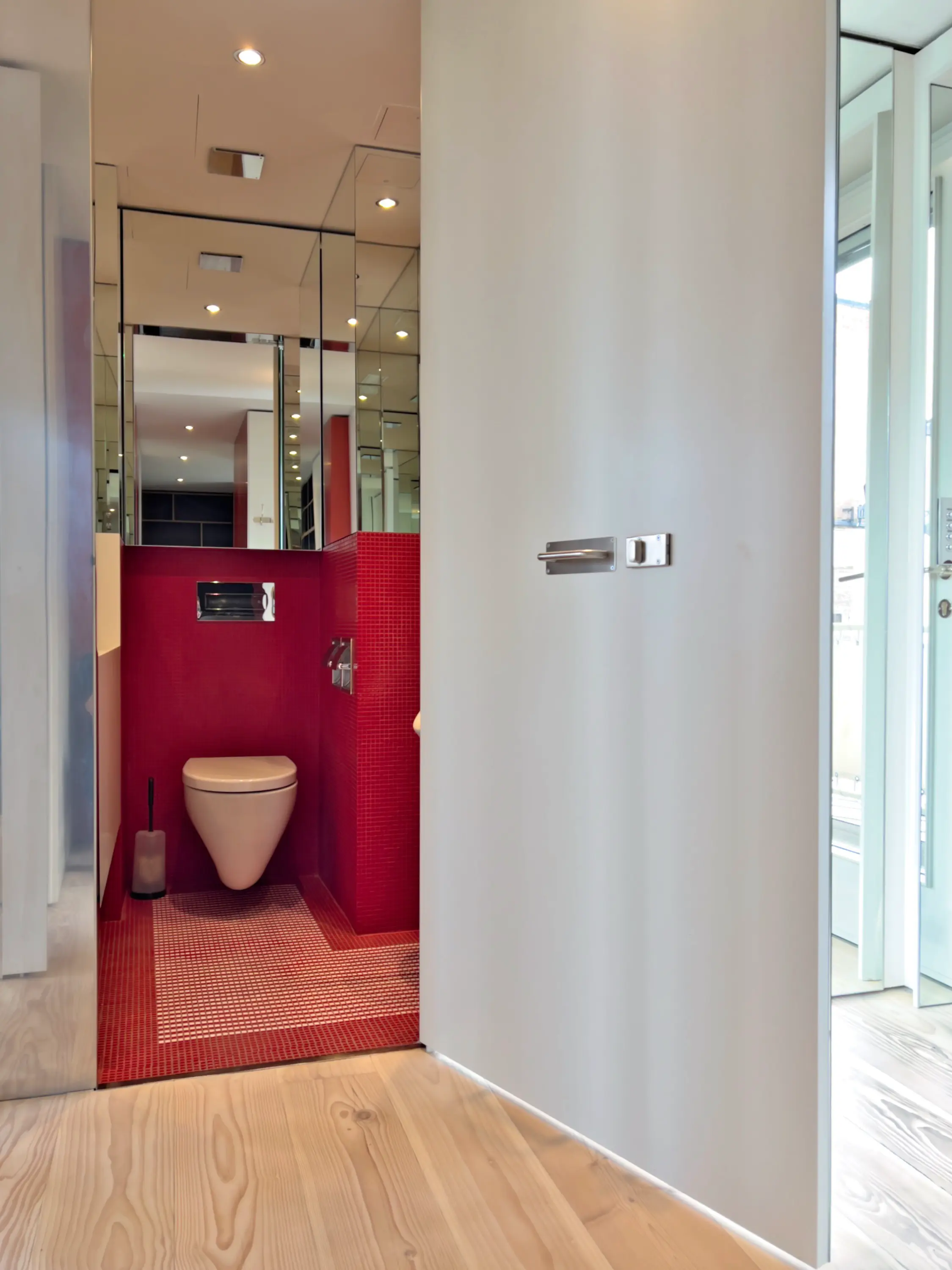 Stilvolles Gäste-WC mit roten Wandfliesen, schwarzem Waschbecken und schwebender Toilette.