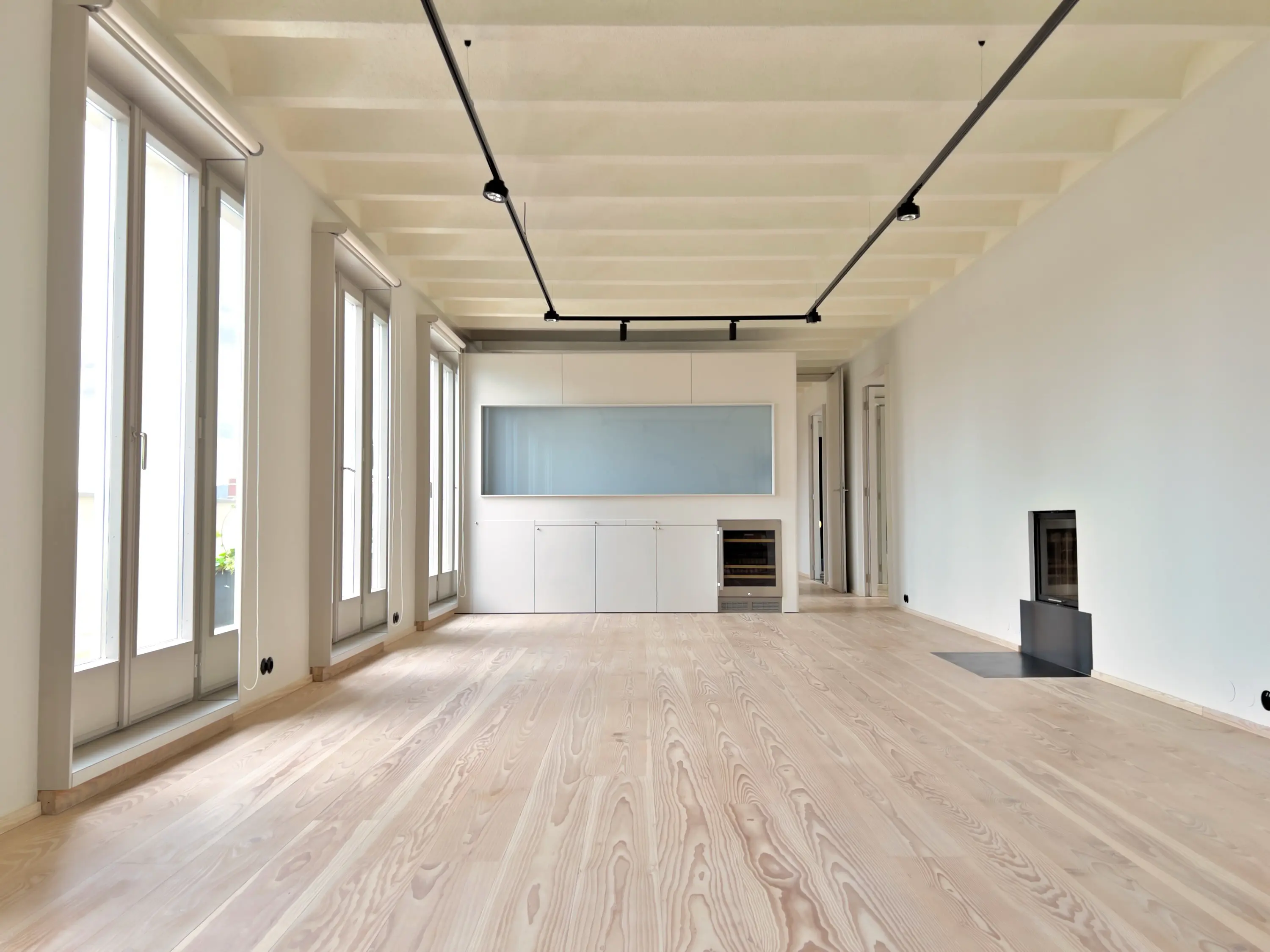 Geräumiges Wohnzimmer mit hohen Decken, indirekter Beleuchtung und großen Fensterfronten.