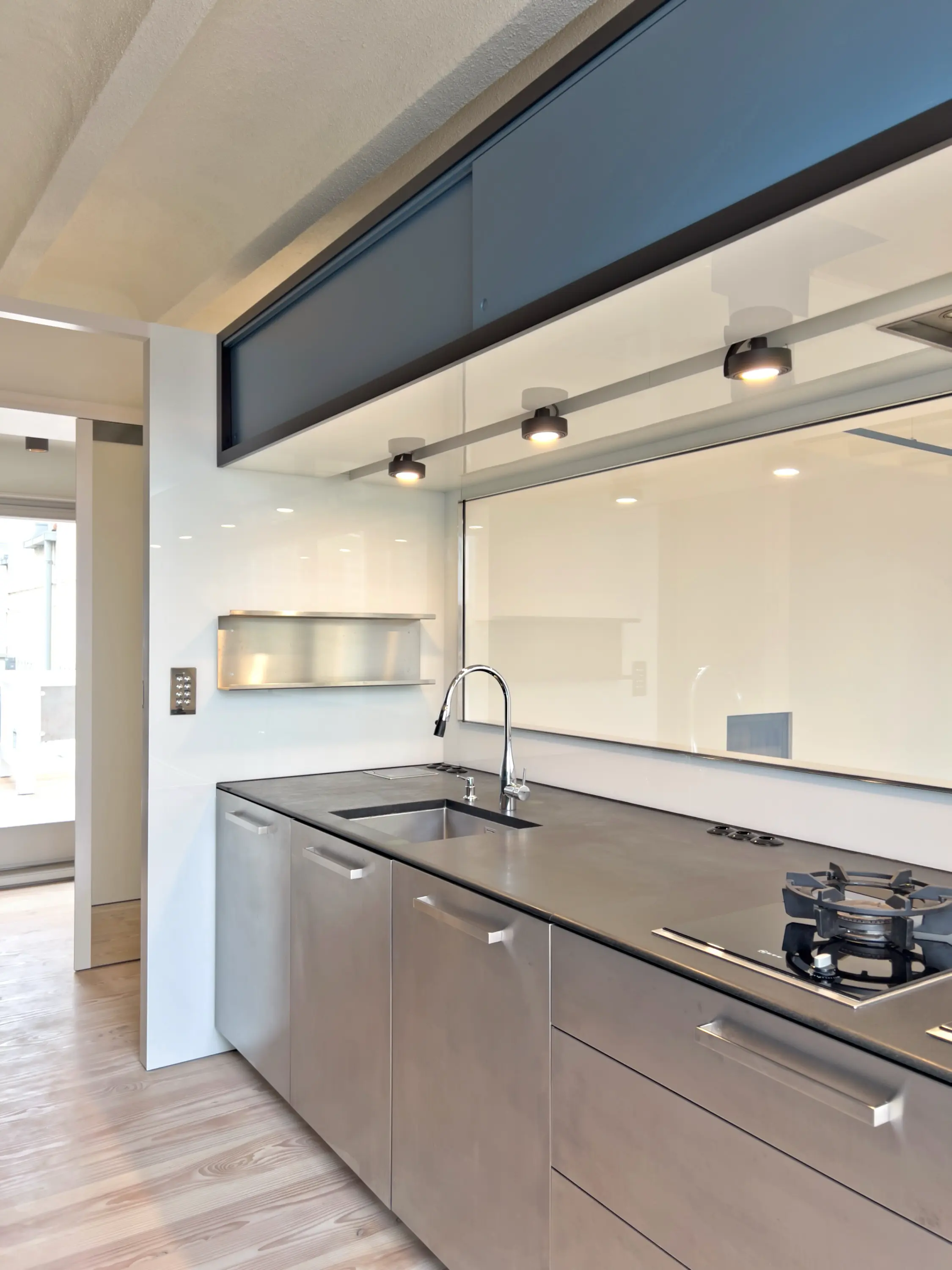 Helle Wohnküche mit zentraler Kochinsel, eingebauten Geräten und viel Tageslicht.