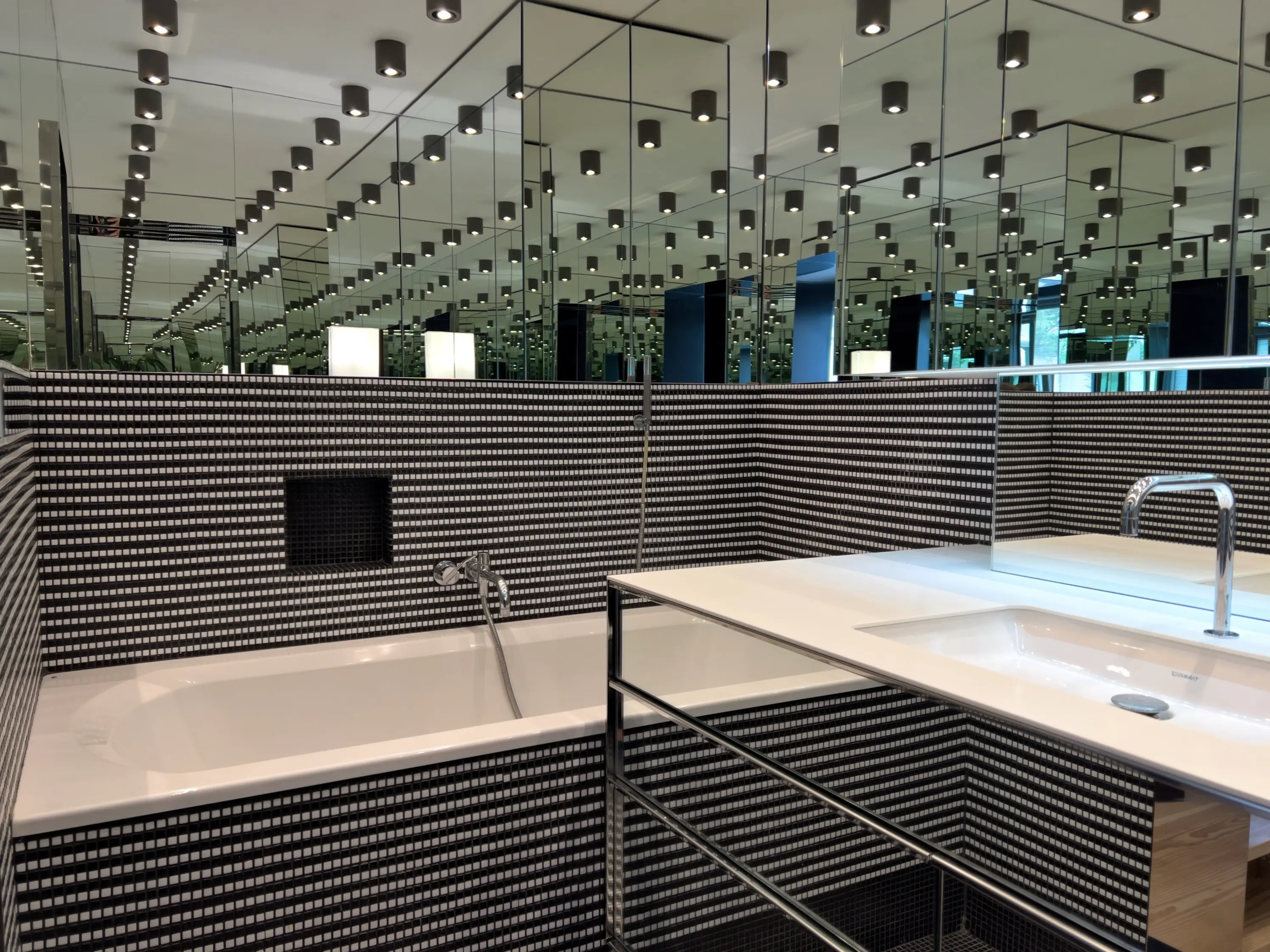 Eindrucksvoller Spiegelraum mit Spiegelwänden und schwarzen Deckenpaneelen.